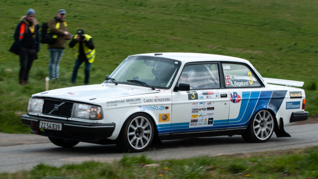 Et par fotografer og en official i DIS RALLY YDING passeres her af Kurt Mejer og Steen Boegelund i den hurtige Volvo 242 Turbo